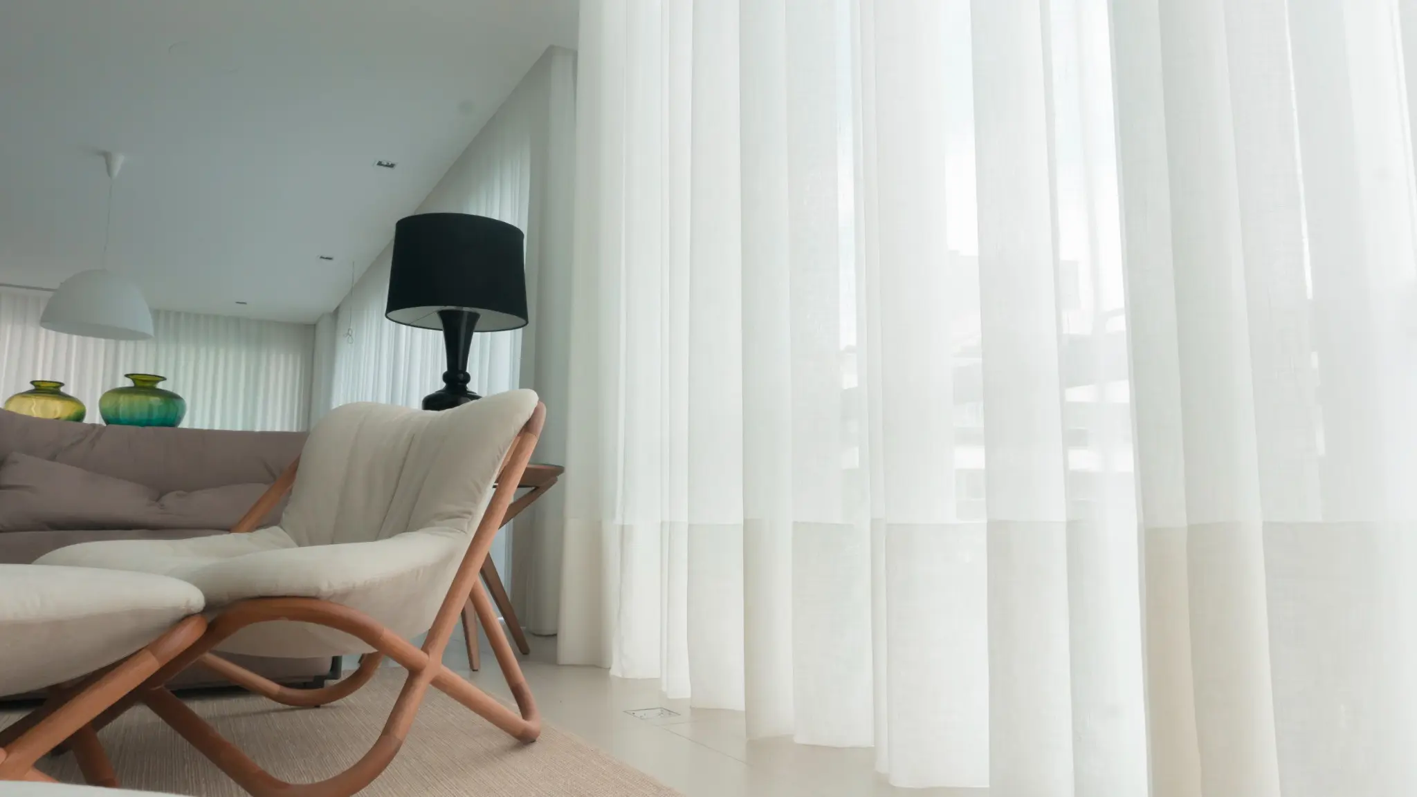 Sala clara com cortinas brancas acompanhando a arquitetura