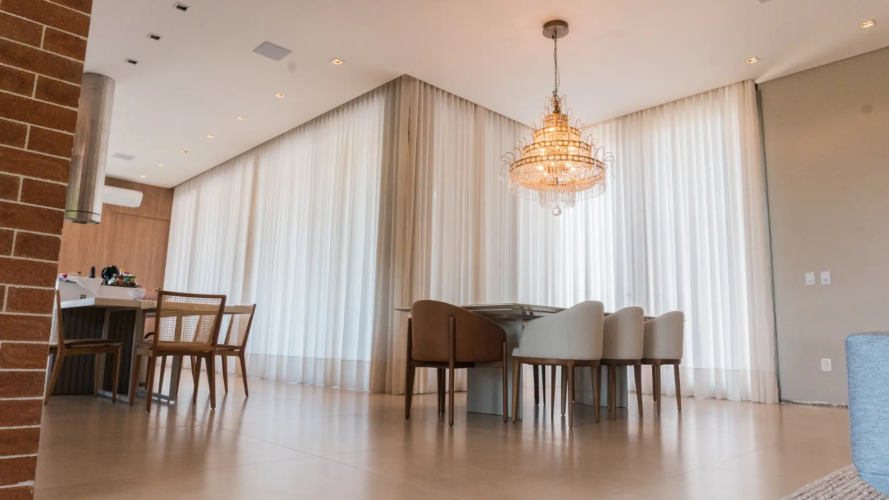Sala de jantar com cortinas brancas contornando o ambiente